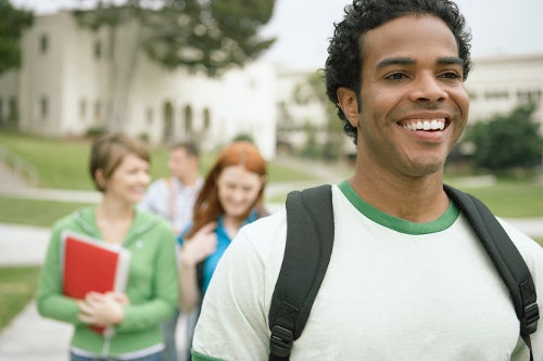A smiling student walking across school campus.