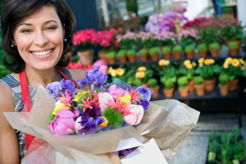 A smiling florist presenting a bouquet of flowers.